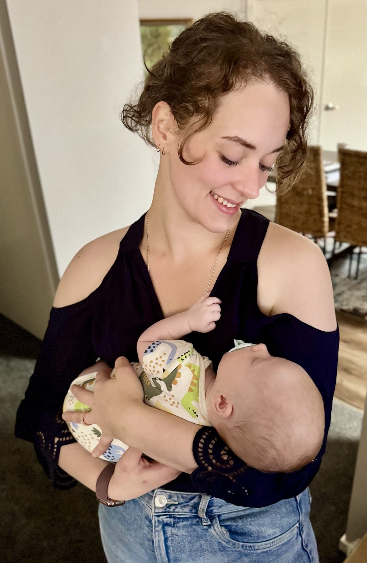 Ksana, founder of Matrescence, smiling as she cradles her baby
